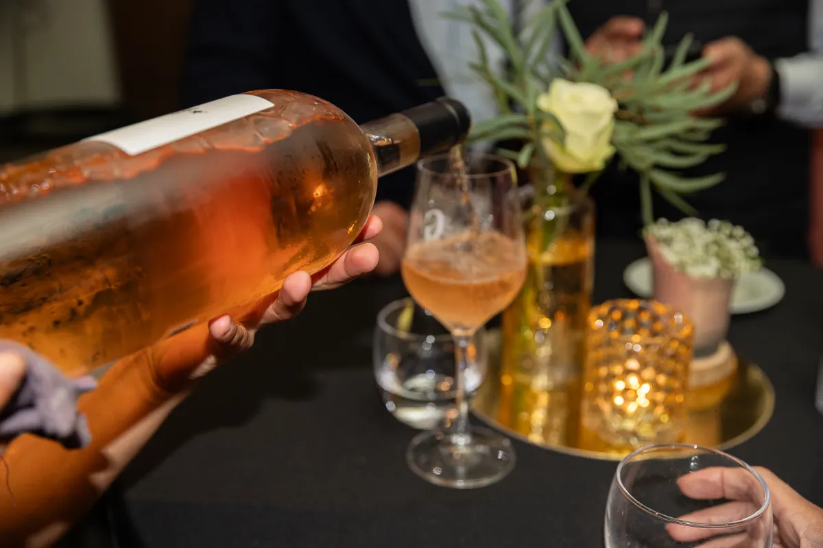 Roséwijn wordt ingeschonken aan een feestelijk gedekte tafel met bloemen en kaarslicht